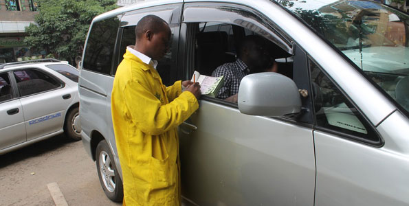 A parking attendant issues a receipt to a motorist in Nairobi. www.businesstoday.co.ke