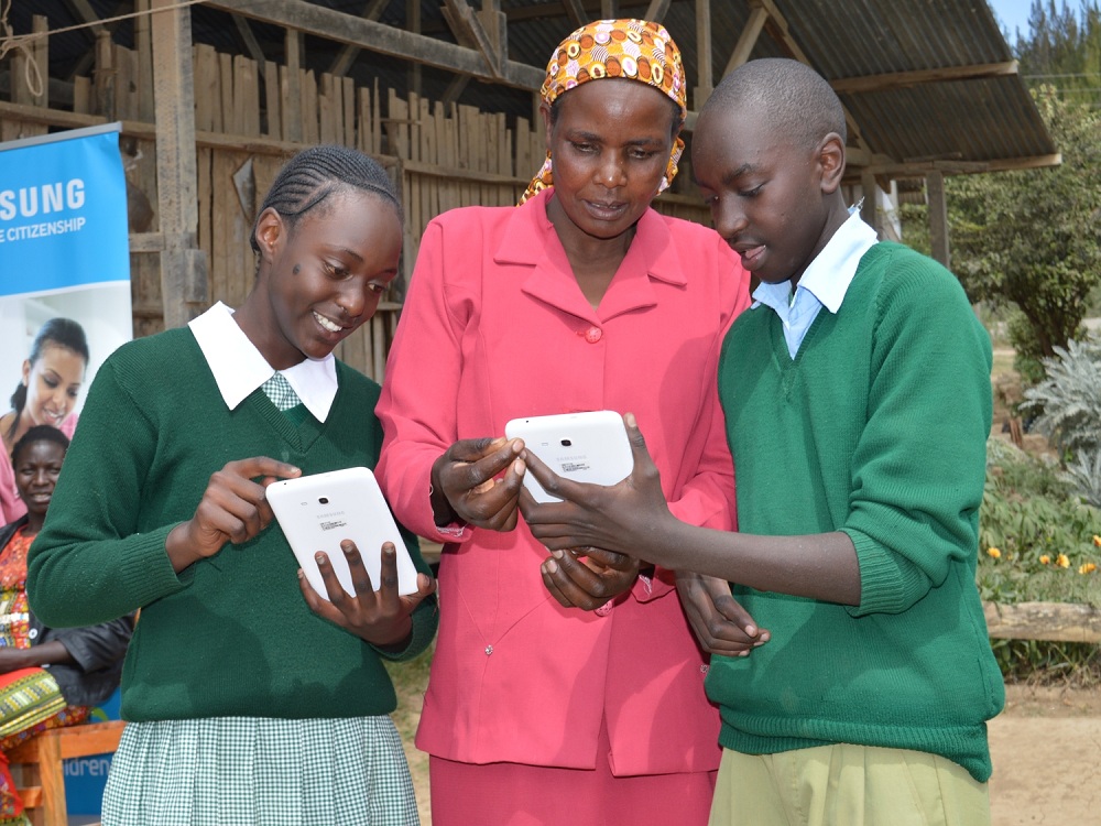 Pupils of Kampi Primary School in Nyeri County show a parent how tablets work. Airtel Kenya as offered free internet access to students to continue learning as coronavirus forces a lock down on many aspects of life. www.businesstoday.co.ke