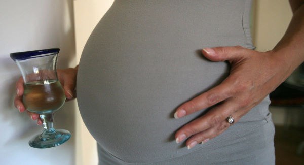 A pregnant women holding a glass of white wine www.businesstoday.co.ke