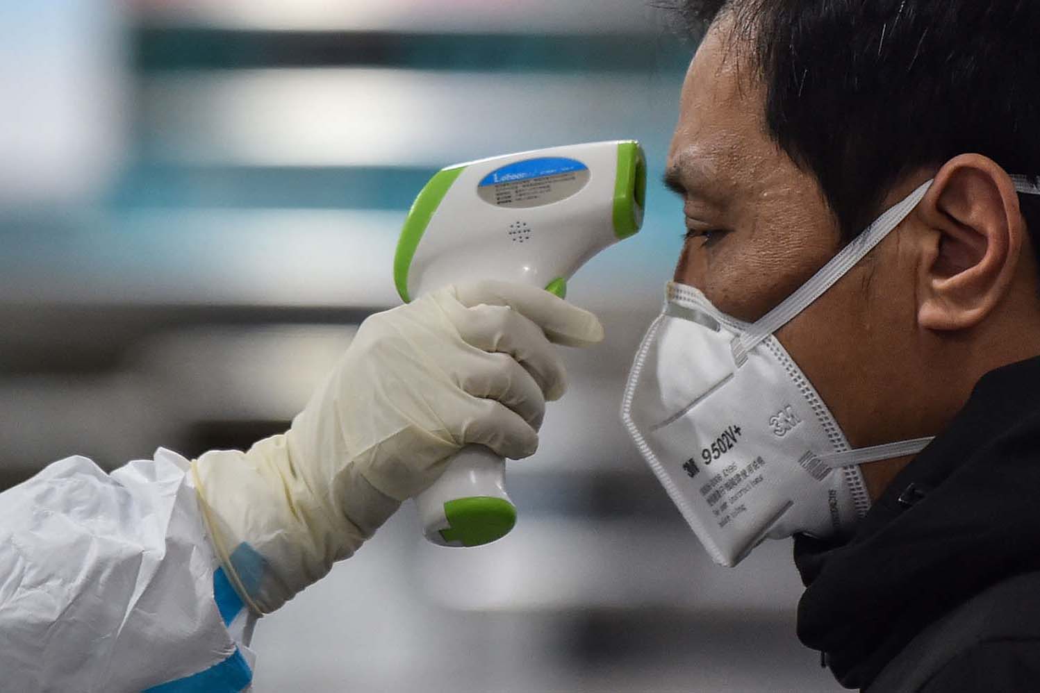 A medical staff member takes the temperature of a man at the Wuhan Red Cross Hospital in China on Jan. 25. The WHO is concerned about the HIV positive and malnourished children as the virus spreads. www.businesstoday.co.ke
