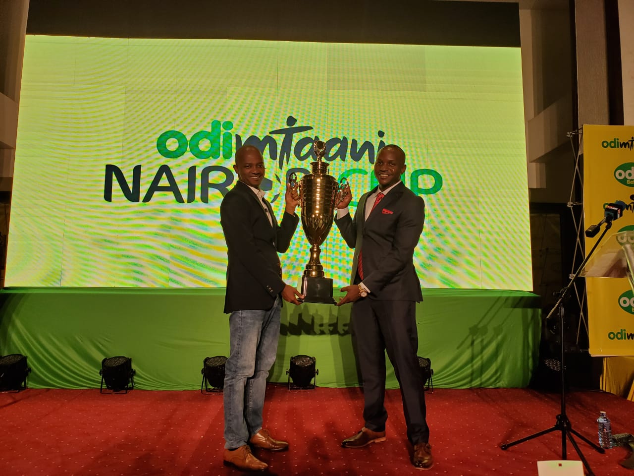 FKF President Nick Mwendwa (left) with Odibets country manager Aggrey Sayi showcase the Odi Mtaani cup. www,businesstoday.co.ke