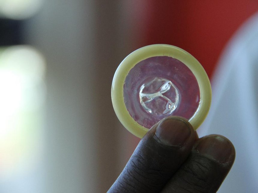 A man holds up a condom