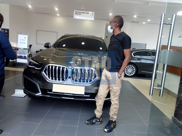 Maina Kageni standing next to his 2020 BMW X6. His collection includes several other high-end cars. [Photo/ The Star]