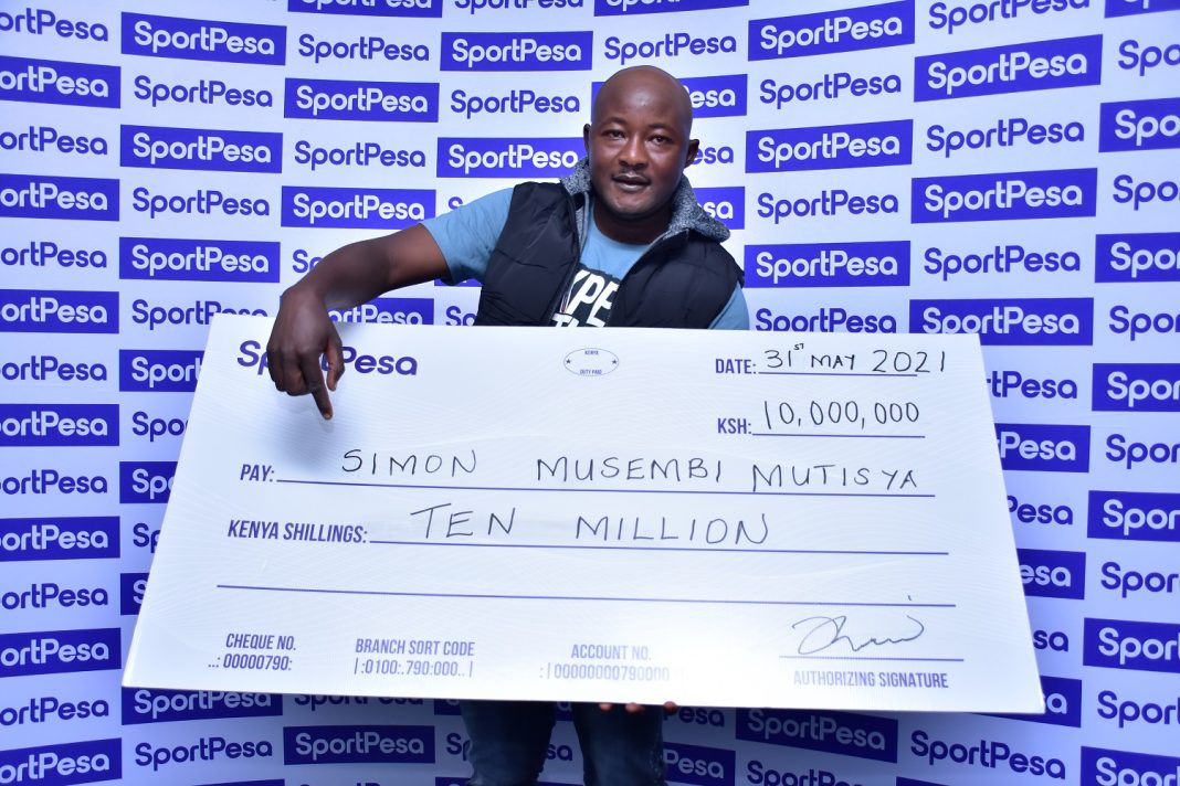 SportPesa Midweek Jackpot winner Simon Musembi, a Machakos based shoe hawker all smiles as he receives his cheque