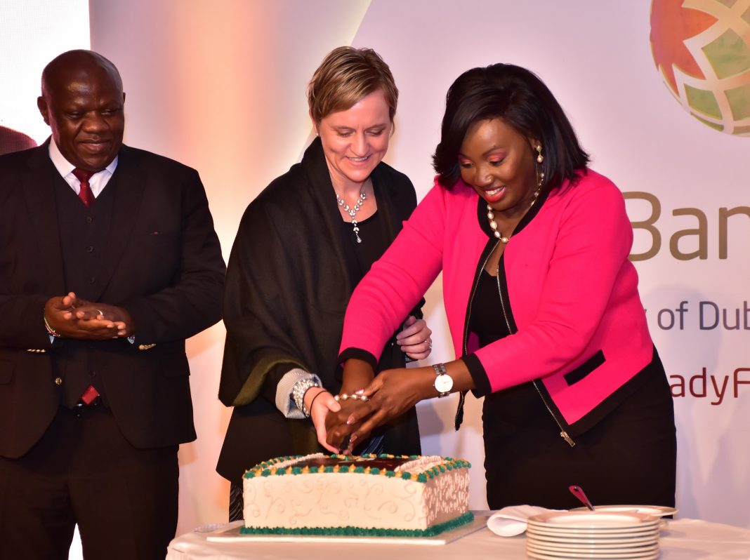 Treasury CAS Eric Wafukho (L) looks on as DIB Bank Kenya Board of Director Alison Blignault (C) and KNCCI Vice Chair Women in Business Nancy Muthoni cut a cake to mark the bank's 4 years Anniversary