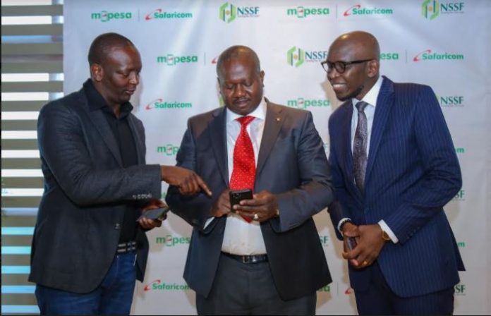 Safaricom PLC,Chief Financial Services Officer, Sitoyo Lopokoiyit (Left) and Safaricom PLC, Chief Enterprise Business Officer, Kris Senanu(Right) demonstrates how the NSSF mini app works to NSSF Managing Trustee, Antony Omerikwa(Center) during the NSSF Mini App launch Breakfast at the Safaricom HQ.