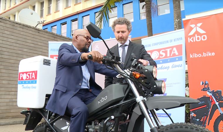 Postal Corporation of Kenya Postmaster General Dan Kagwe (Left) tries his hand on one of the Kibo motorcycles when he flagged off a fleet of 40 motorcycles to support the corporation's last mile service.