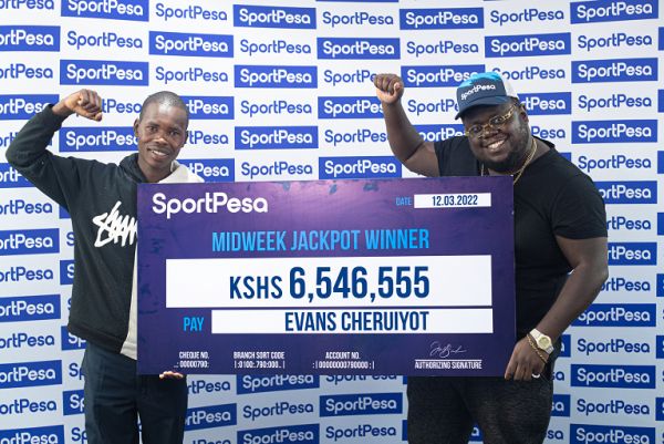 Evans Cheruiyot (Left) celebrates with his winners cheque of Ksh. 6,546,555 after he won the Sportpesa midweek jackpot.