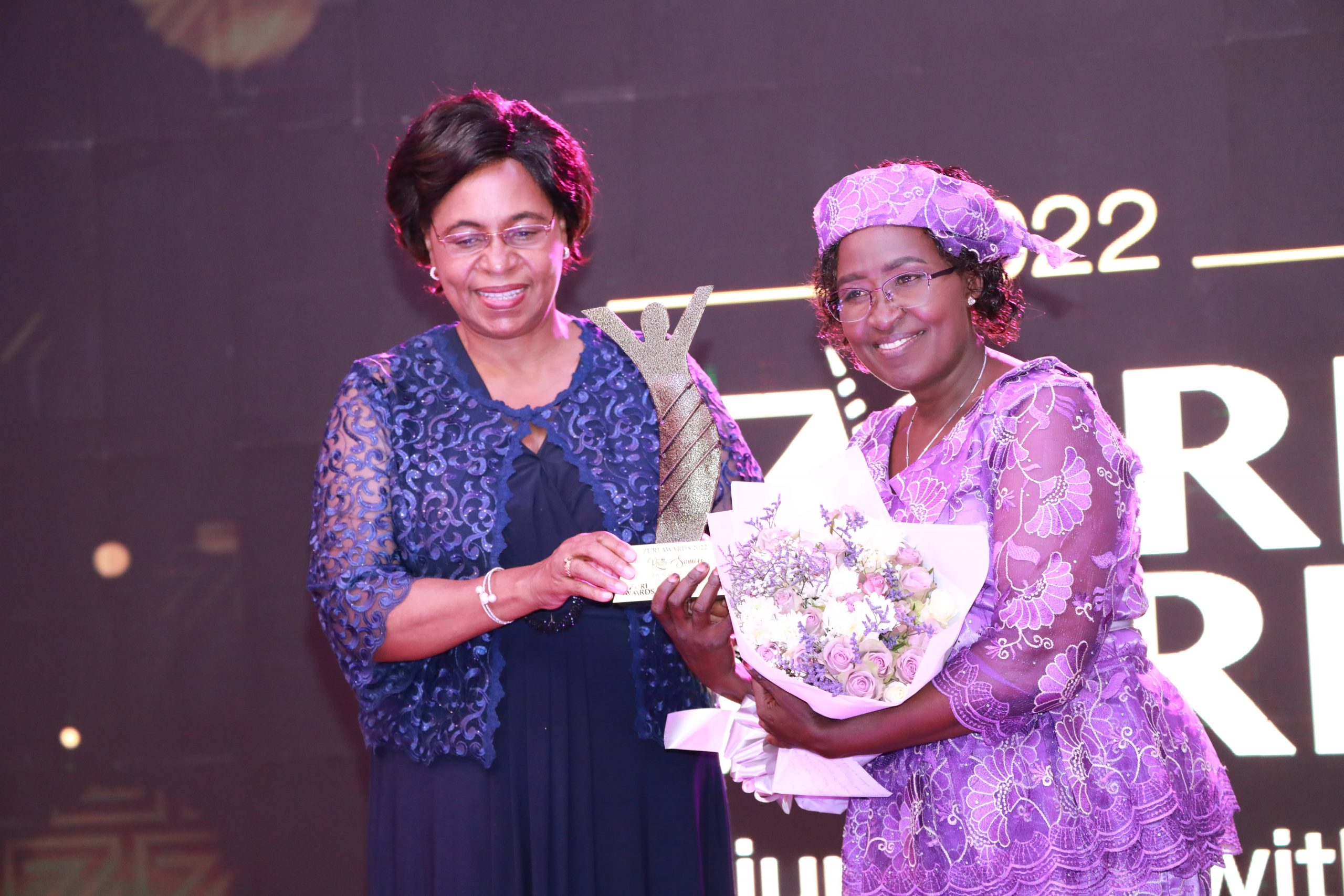 Margaret Kobia, Cabinet Secretary, Ministry of Public Service and Gender giving an award to Ruth Samoei for her role in facilitating disadvantaged deaf communities to favourably compete for available business opportunities in an already saturated market at the 2022 ZURI AWARDS held in Nairobi.