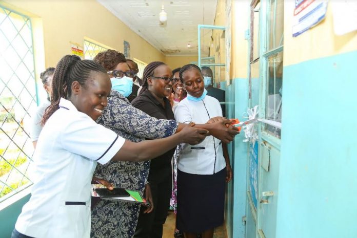 Safaricom PLC Area sales Manager- Greater Western Region, Mercy Kiprop (second right), cuts a ribbon during the official handover of an equipped maternity wing at Lukhome Community Dispensary in Trans- Nzoia County.