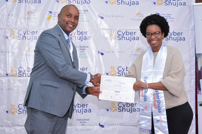 Joseph Mathenge, Serianu Chief Operating Officer (left) presents a Security Analyst Completion Certificate to Brenda Kamangara (right) during the Cyber Shujaa Second Cohort Graduation.