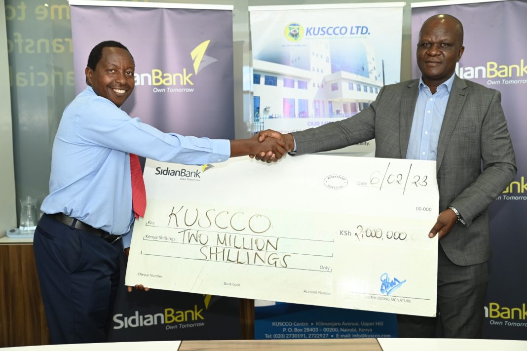 Left : Sidian Bank CEO Chege Thumbi handing over a cheque to KUSCCO CEO Mr George Ototo during a ceremony at Sidian Headquarter in Nairobi .
