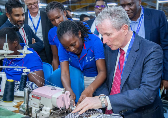 Hela Intimates Stitching Technician Ms Rhoda Mwikali (Second right) assists Norfund CEO Tellef Thorleifsson (right) to stitch a garment during a tour of the Hela Intimates EPZ Ltd factory at Athi River EPZ as other executives including Norwegian Ambassador to Kenya Amb. Gunnar Andreas Holm (second left) looks on. Norfund has sealed a US$ 14 million financing agreement with Hela Intimates EPZ Ltd to bolster the development of its manufacturing operations in East Africa.