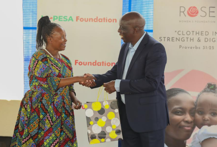 M-Pesa Foundation Trustee, John M Ohaga receiving a gift from ROSE beneficiary, Margaret Muriuki after the official launch of Micro-Enterprise accelerator program in partnership with M-Pesa and ROSE foundation at Dagoretti.