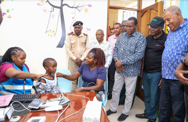 From (R) to (L) Lamu County governor Issa Timamy, Safaricom Foundation Chairperson Joseph Ogutu, together with Lamu Deputy Governor, Raphael Munyu watches keenly as Njeri Kamau a clinical officer at Mpeketoni Sub-County Hospital examining a young boy together with his mother Mary Waweru through the use of telemedicine unit program Daktari smart at Mpeketoni Sub-County Hospital, Lamu County.