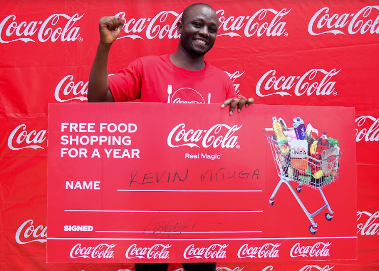 Kevin Mituga holding a dummy cheque as the first winner of the Coca-Cola promotion in Nairobi. He won a years’ worth of food shopping courtesy of Coca-Cola.