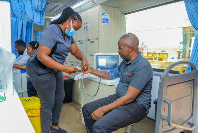 Sarafina Omagwa, a nurse, monitors Safaricom and M-PESA Foundation Senior Programmes Manager Henry Kilonzo’s blood pressure in their mobile clinic during a medical Camp held at Olympic Primary School in Kibera.