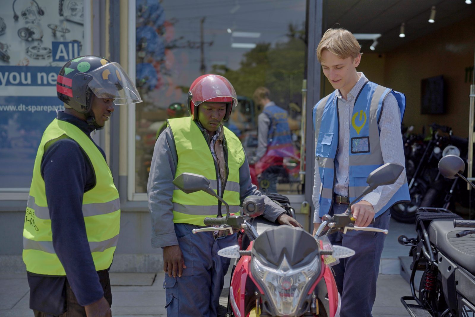 (L-R) Mogo Electric Vehicles Financing Manager, Rauls Leitis interacting with boda boda customers, Peter Mungai and Joshua Mutune at Mogos e-bike shop on Jogoo road.