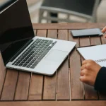 Worker with notebook and laptop in street cafe