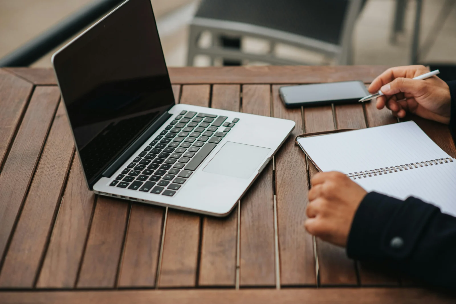 Worker with notebook and laptop in street cafe