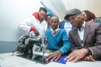 Safaricom CEO Dr. Peter Ndegwa (Right), Catherine Wangari, a student at Mumbi Primary School and Wangui Mwangi (left), a teacher at the school, at the Home Science laboratory during the handover of learning facilities by M-Pesa Foundation.