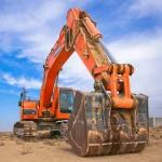 Low Angle Photography of Orange Excavator Under White Clouds