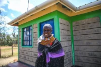 Selina, a homeowner from Nanyuki poses for a photo outside her home constructed in collaboration with Habitat for Humanity Kenya