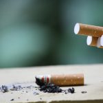 Cigarette with ashes on surface, highlighting tobacco use
