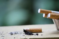 Cigarette with ashes on surface, highlighting tobacco use